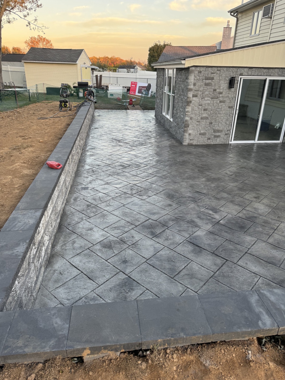 Stamped concrete patio with matching retaining wall at sunset