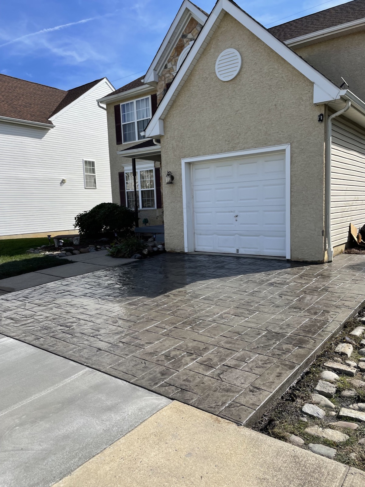 Dark stamped concrete driveway in front of a stucco home